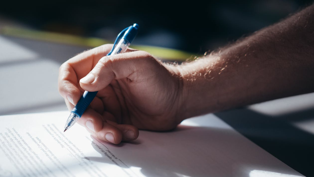 A person signing an important document, which is part of the passport application process.